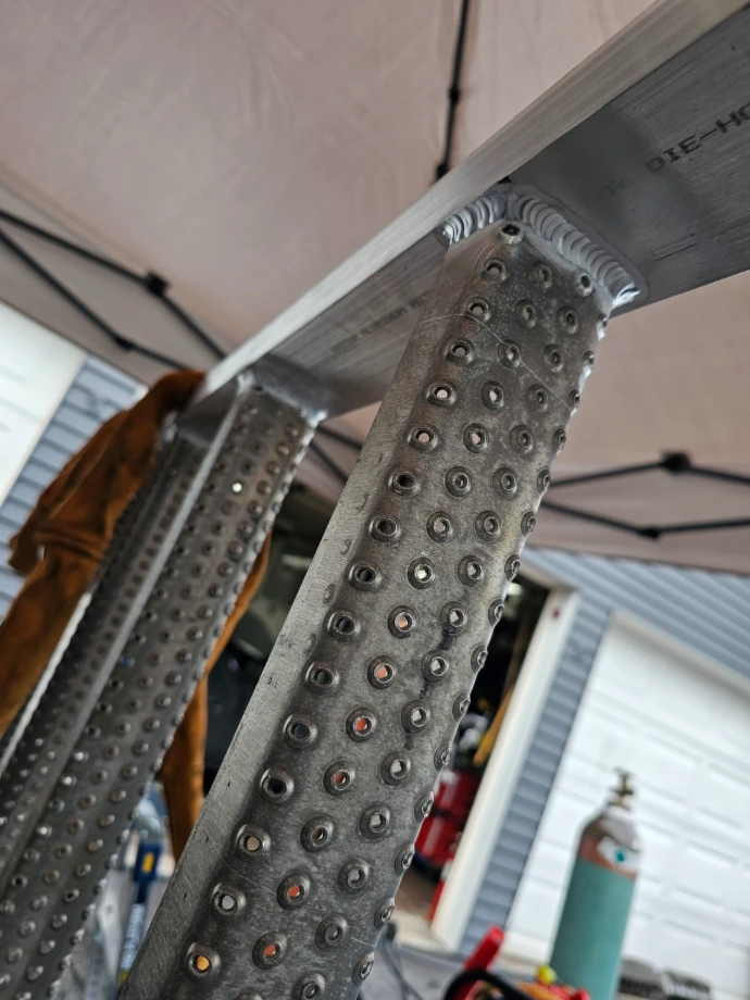 Close-up of TIG-welded aluminum ladder rungs joined to a rectangular frame