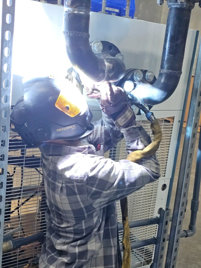 Welder performing on-site repair on industrial equipment