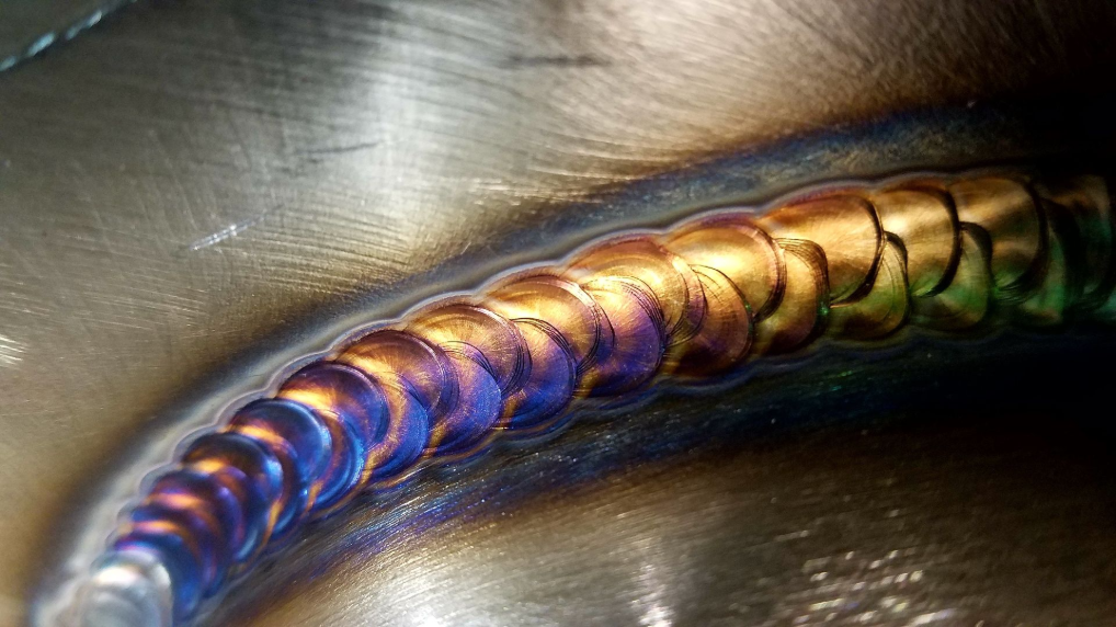 Close-up of a TIG weld bead with purple and gold heat coloration
