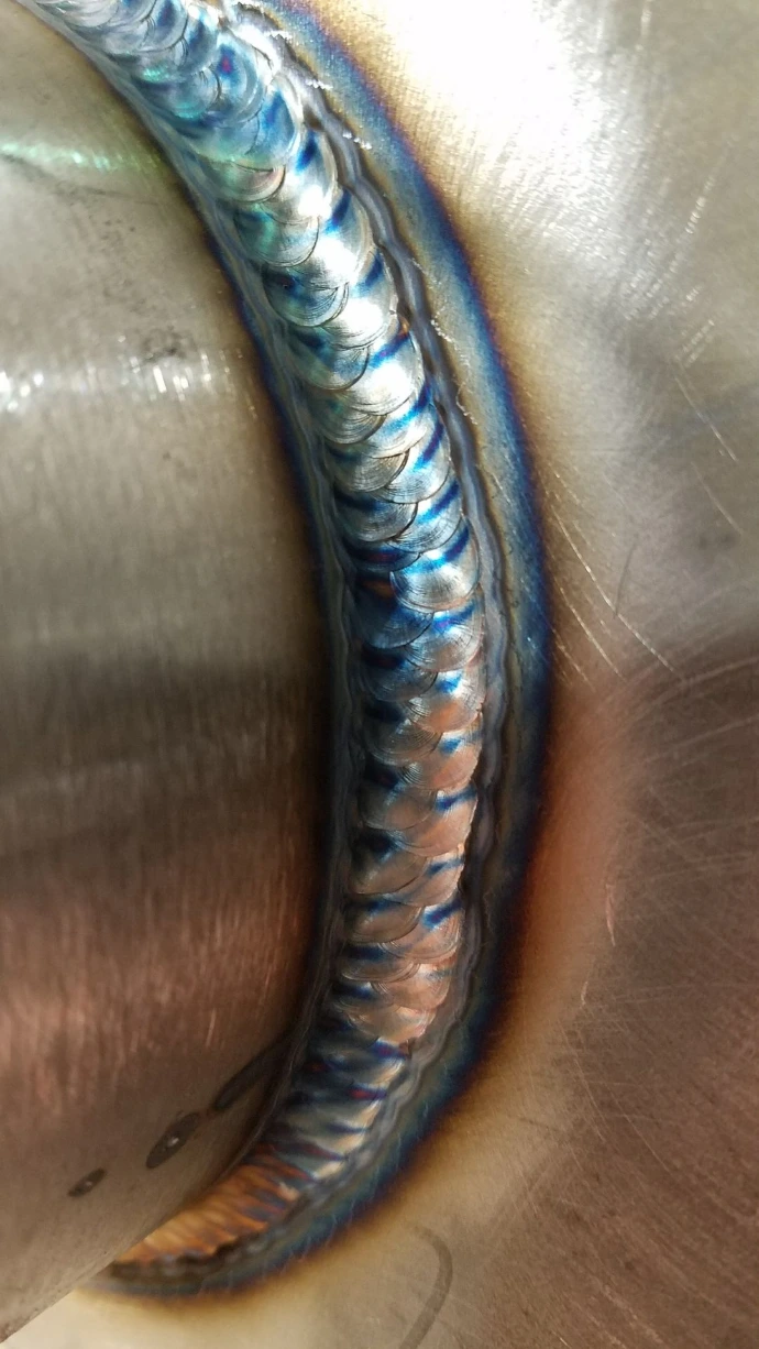 Close-up of an evenly spaced TIG weld bead on curved metal