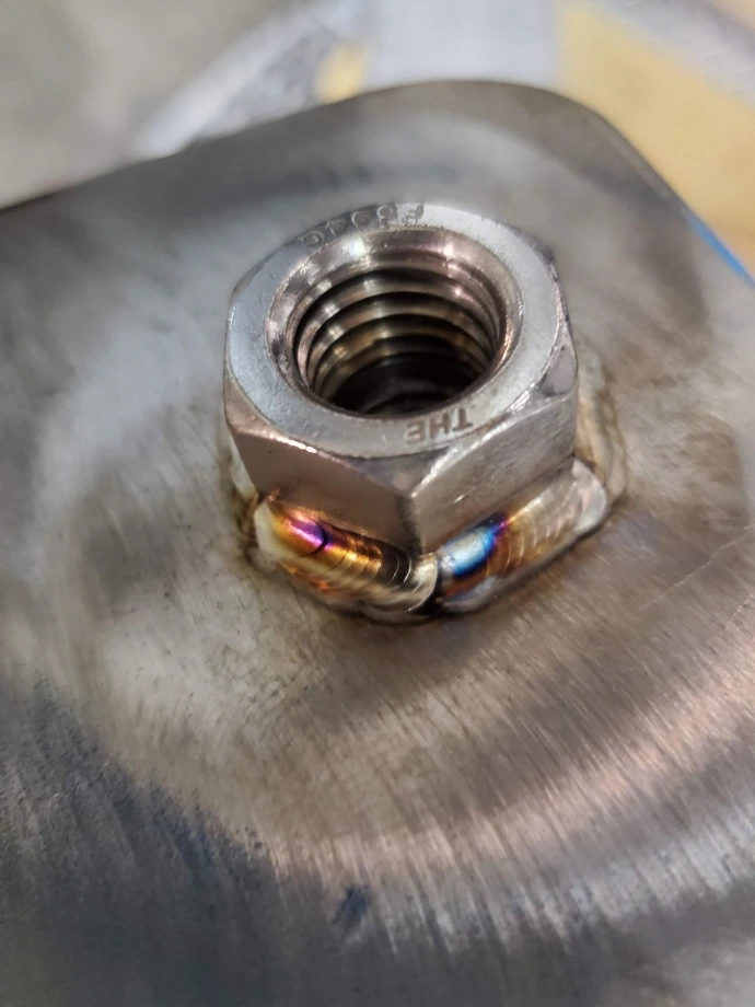 Stainless steel nut TIG-welded to a metal surface